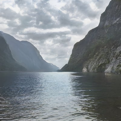 A body of water surrounded by mountains under a cloudy sky