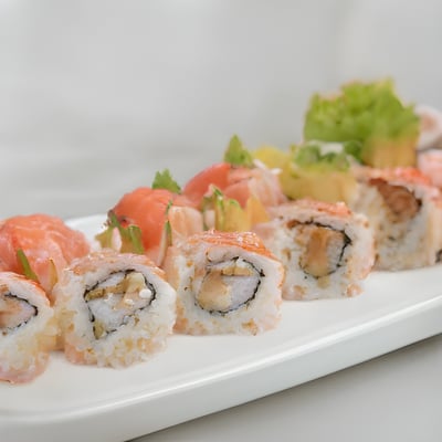 A white plate topped with sushi and vegetables