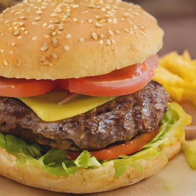 A hamburger with cheese, tomato, lettuce and tomato slices