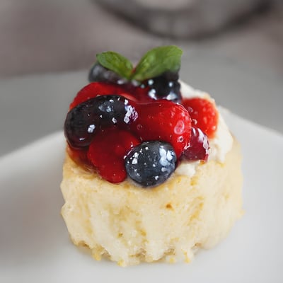 A small pastry with berries and cream on a white plate