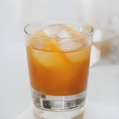 A glass of orange juice with ice on a table