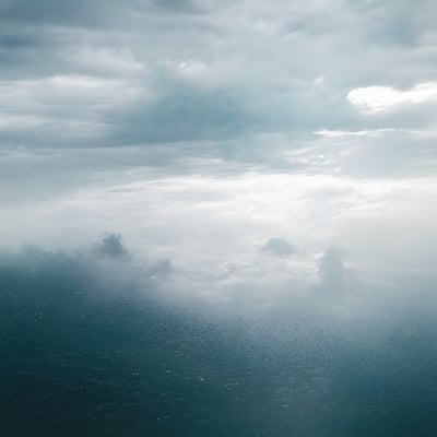 A plane flying through a cloudy sky over the ocean