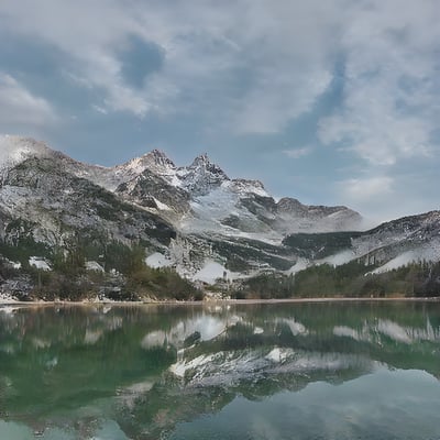 A mountain range is reflected in the still water of a lake