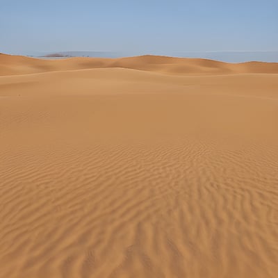 A large sandy area with a blue sky in the background