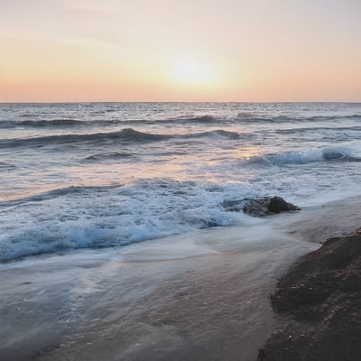 A person standing on a beach holding a surfboard