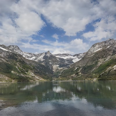 A lake surrounded by mountains under a cloudy sky