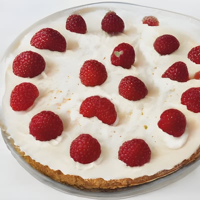 A cake with white frosting and raspberries on top