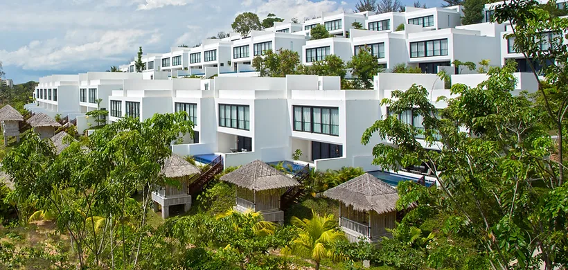 A group of white buildings with trees and blue skyDescription automatically generated