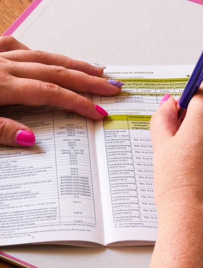 schrijven met pen in boekje met tabellen en financiele gegevens
