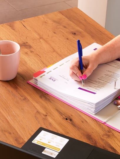 schrijven in map aan houten tafel met koffiekop en laptop