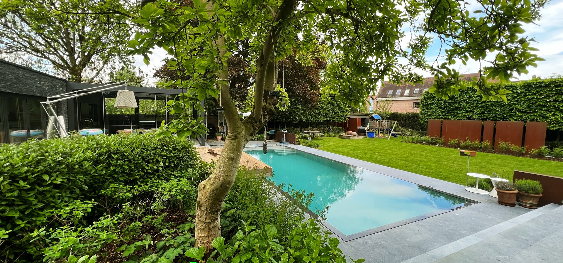 zwembad in tuin met moderne woning en speeltuin