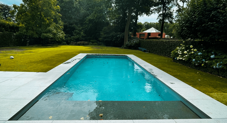 zwembad met grijze tegels en bosrijke omgeving