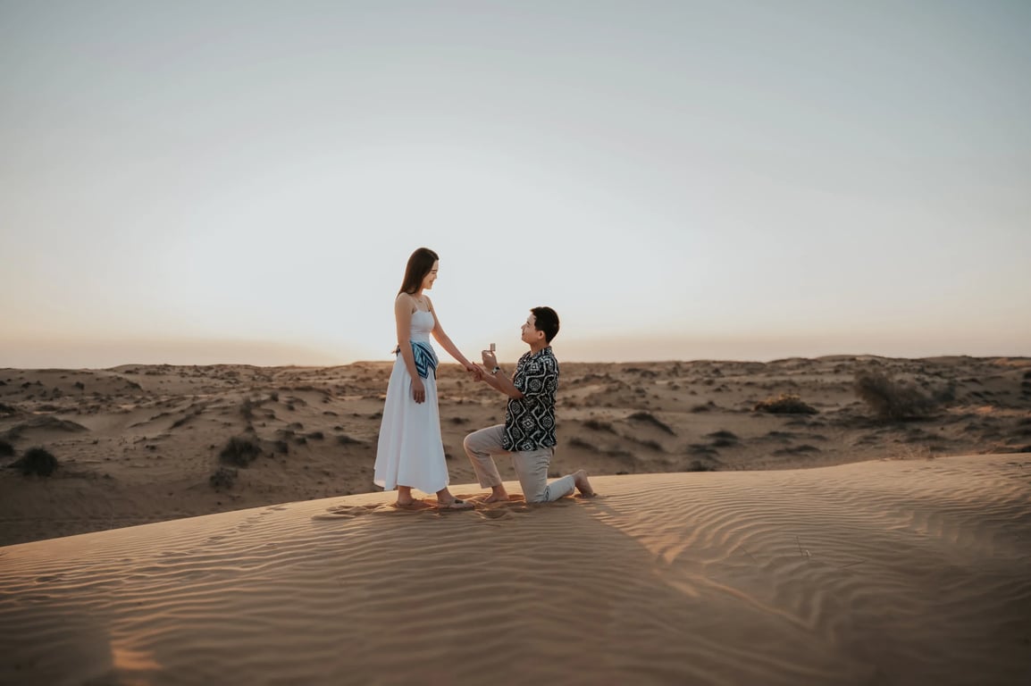 Couple on a dune in Dubai during their proposal moment