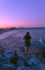  Person standing on rocks by the water at sunset