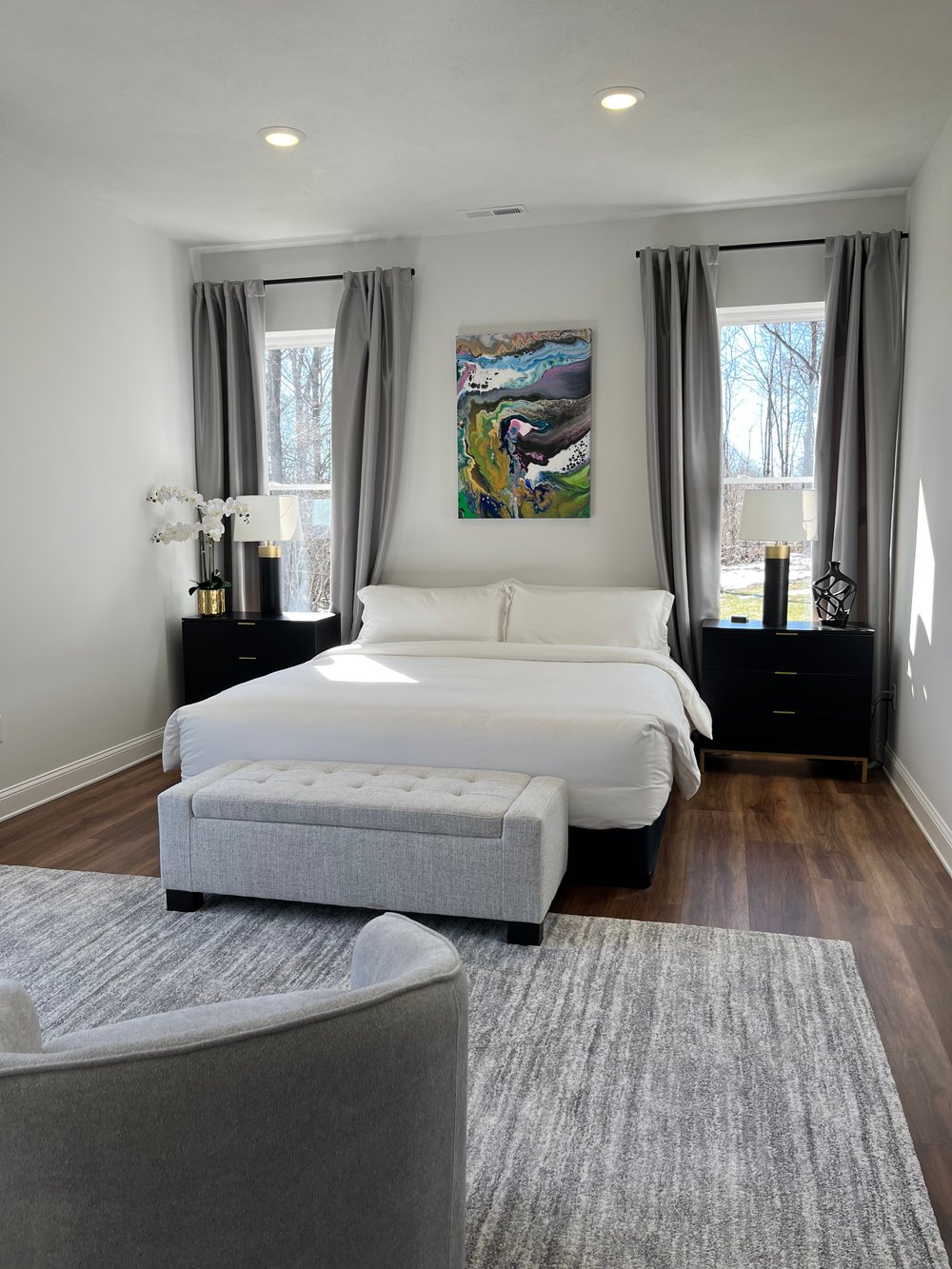 Bedroom 1 with bed centered between two tall windows