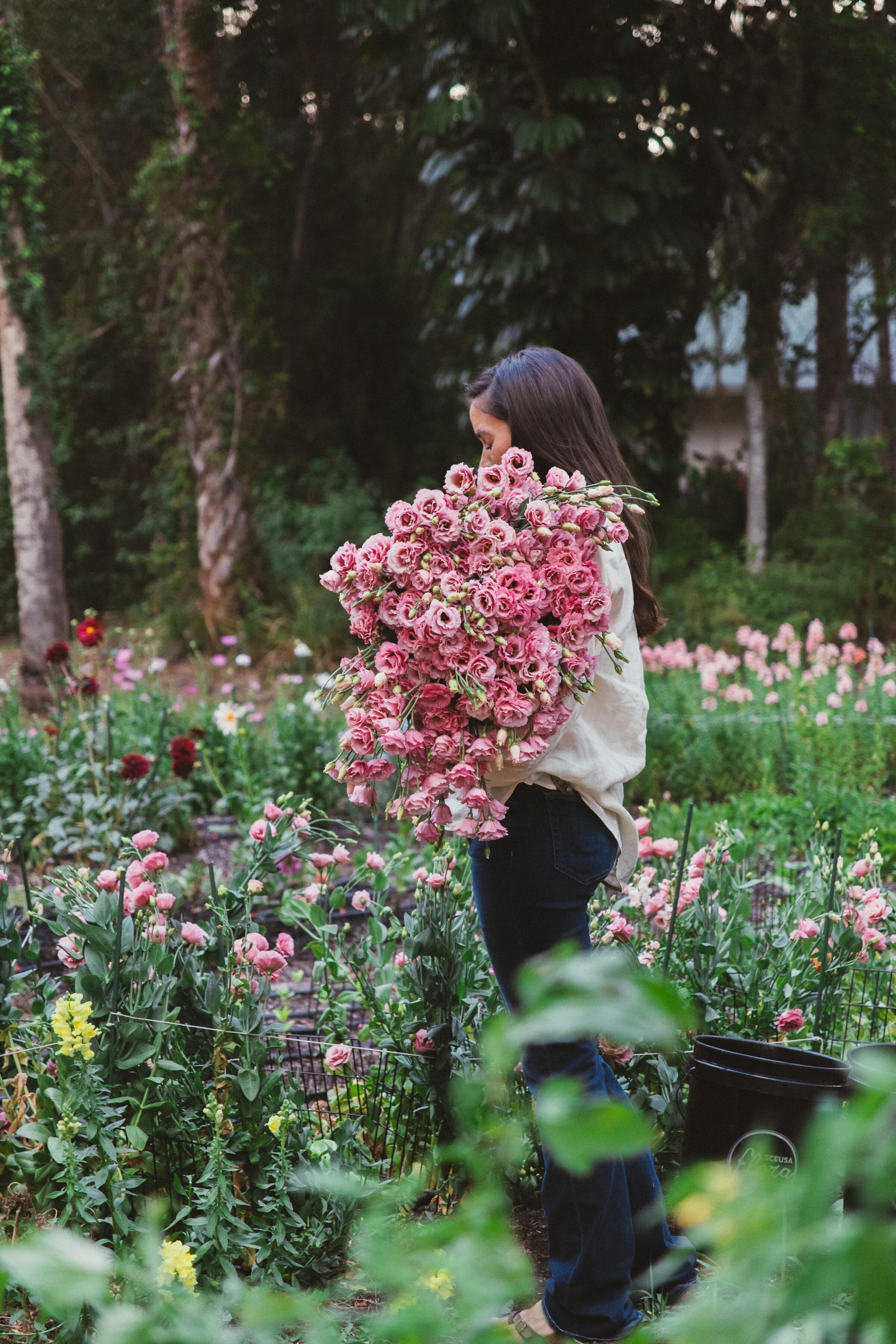 Mia smiling behind a vast bouquet of pink lisianthus picked from the Naples farm