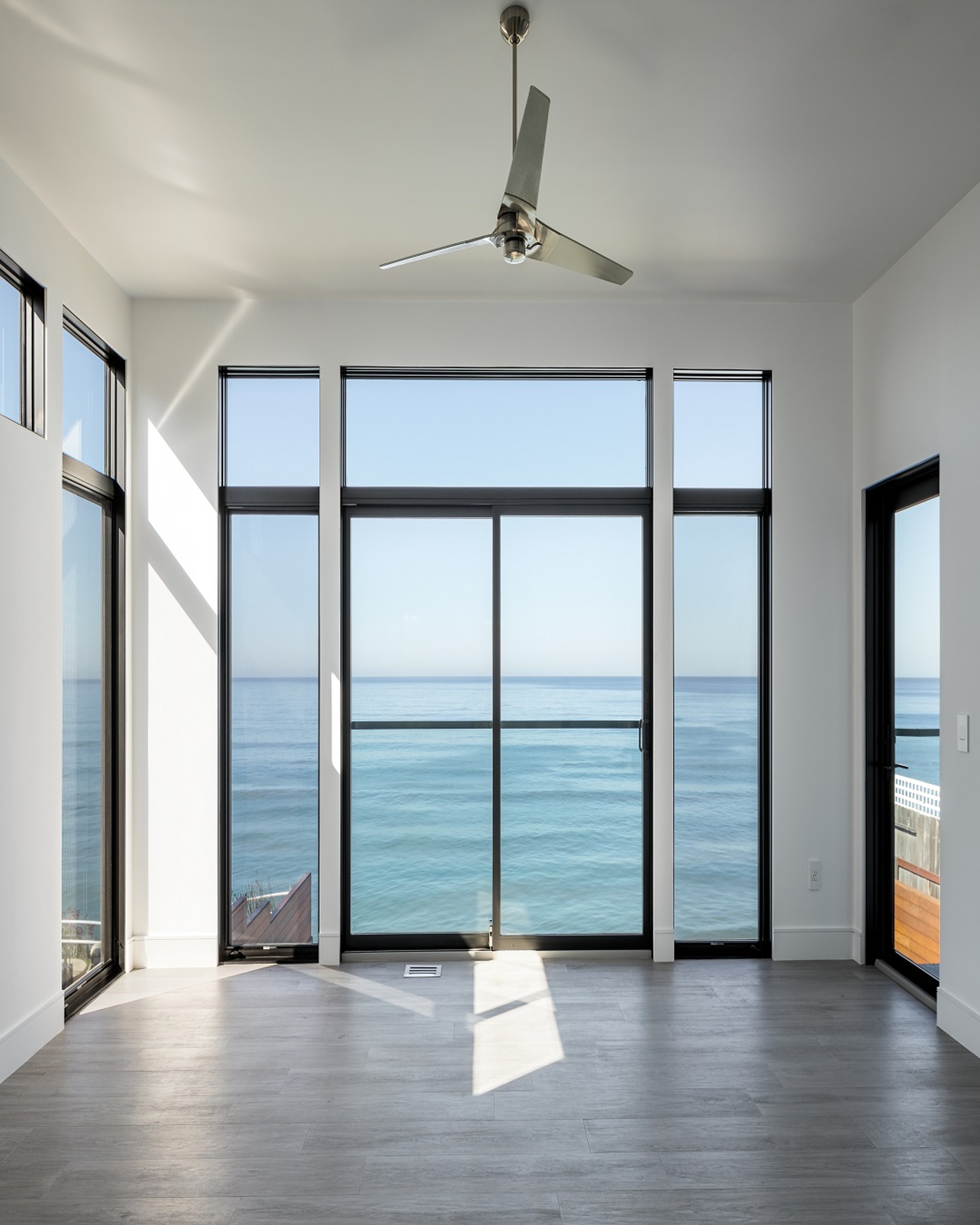 Floor-to-ceiling dark-framed Andersen windows facing the water