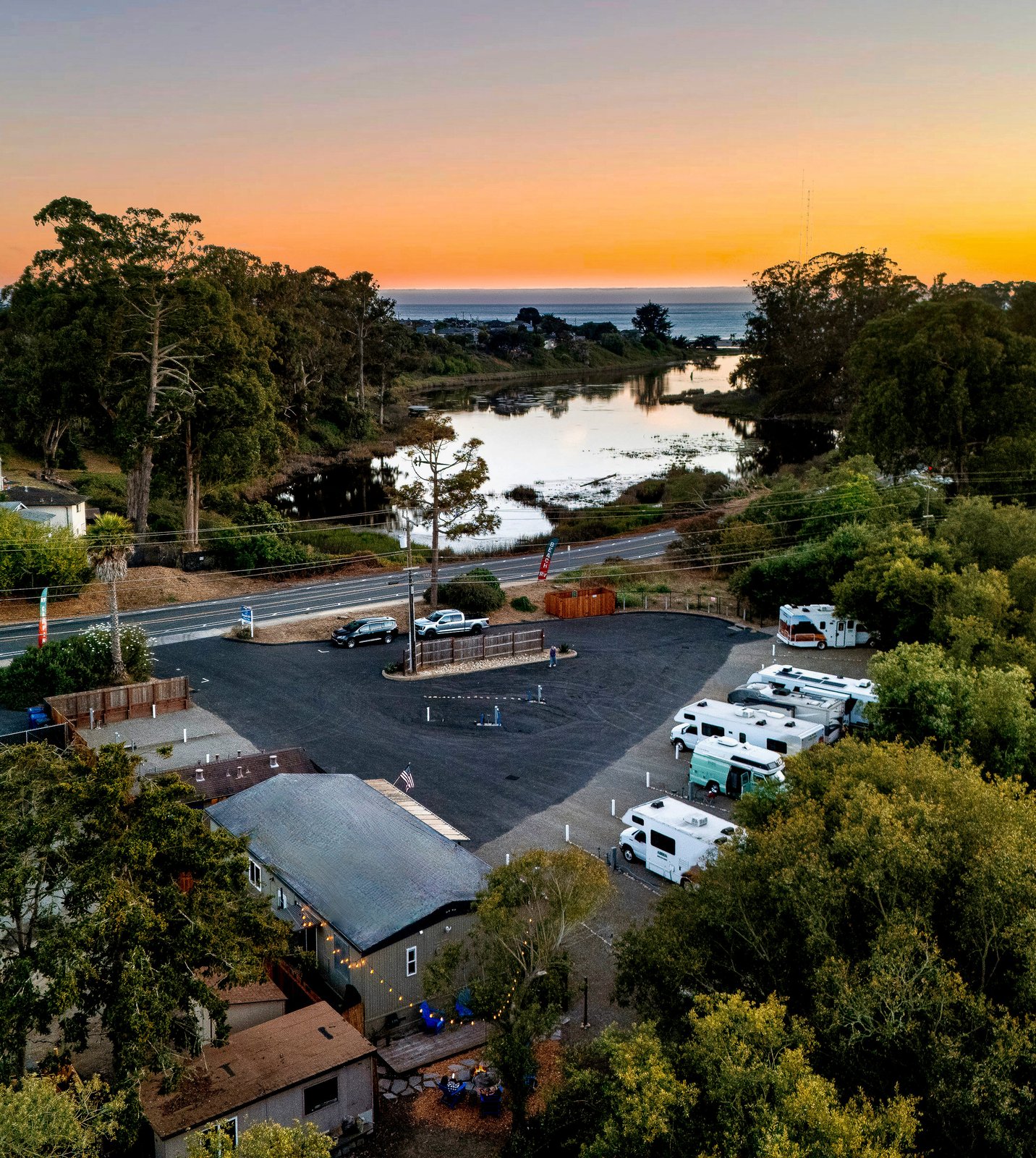 Aerial view of Beach RV Pleasure Point, with Corcoran Lagoon across the road and the ocean beyond at sunset.