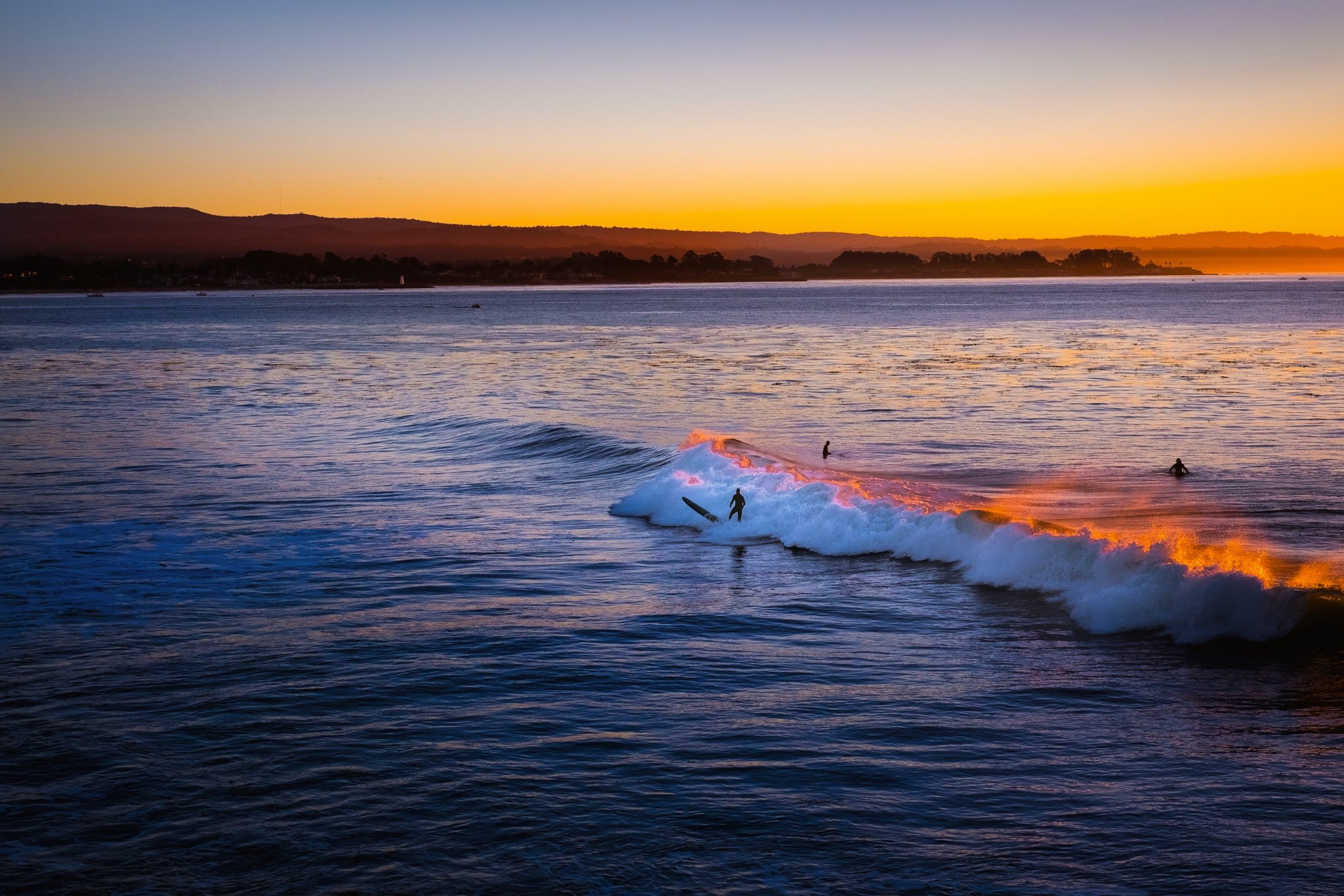 Sunset over Monterey Bay at Beach RV Pleasure Point, surfers in the water