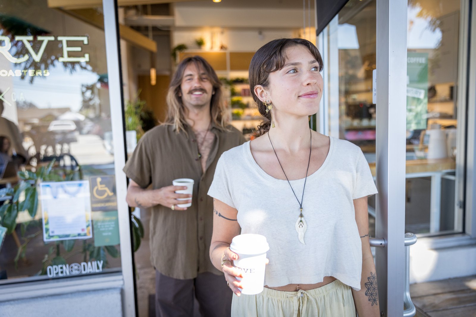 Two people outside a café on 41st Avenue, one holding a coffee cup