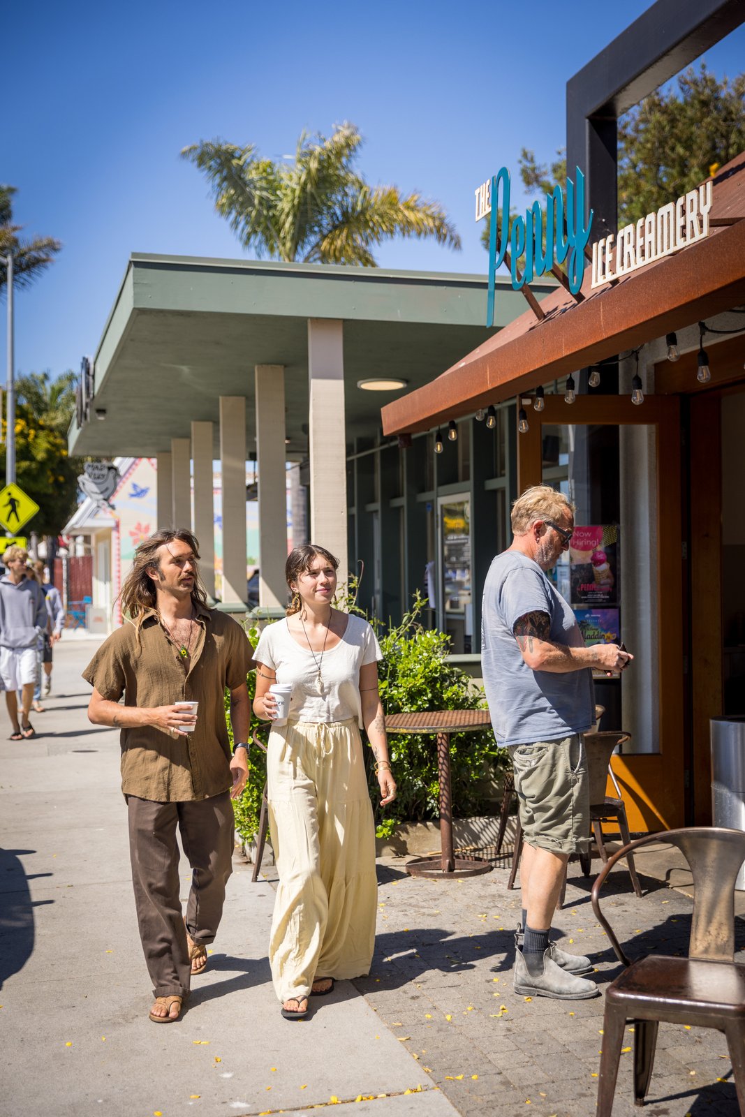 Two people walking past shops and café tables on 41st Avenue.