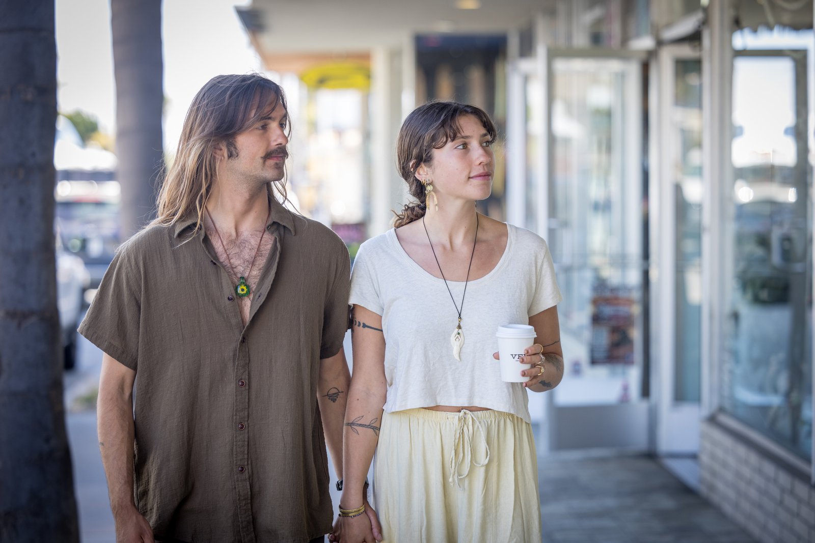 Two people holding hands beside storefronts on 41st Avenue, one holding a coffee cup