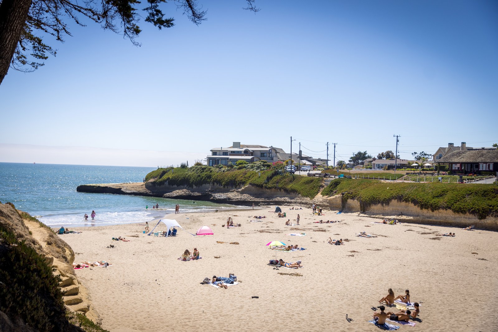 Beachgoers on the sand at Sunny Cove beneath the coastal headland