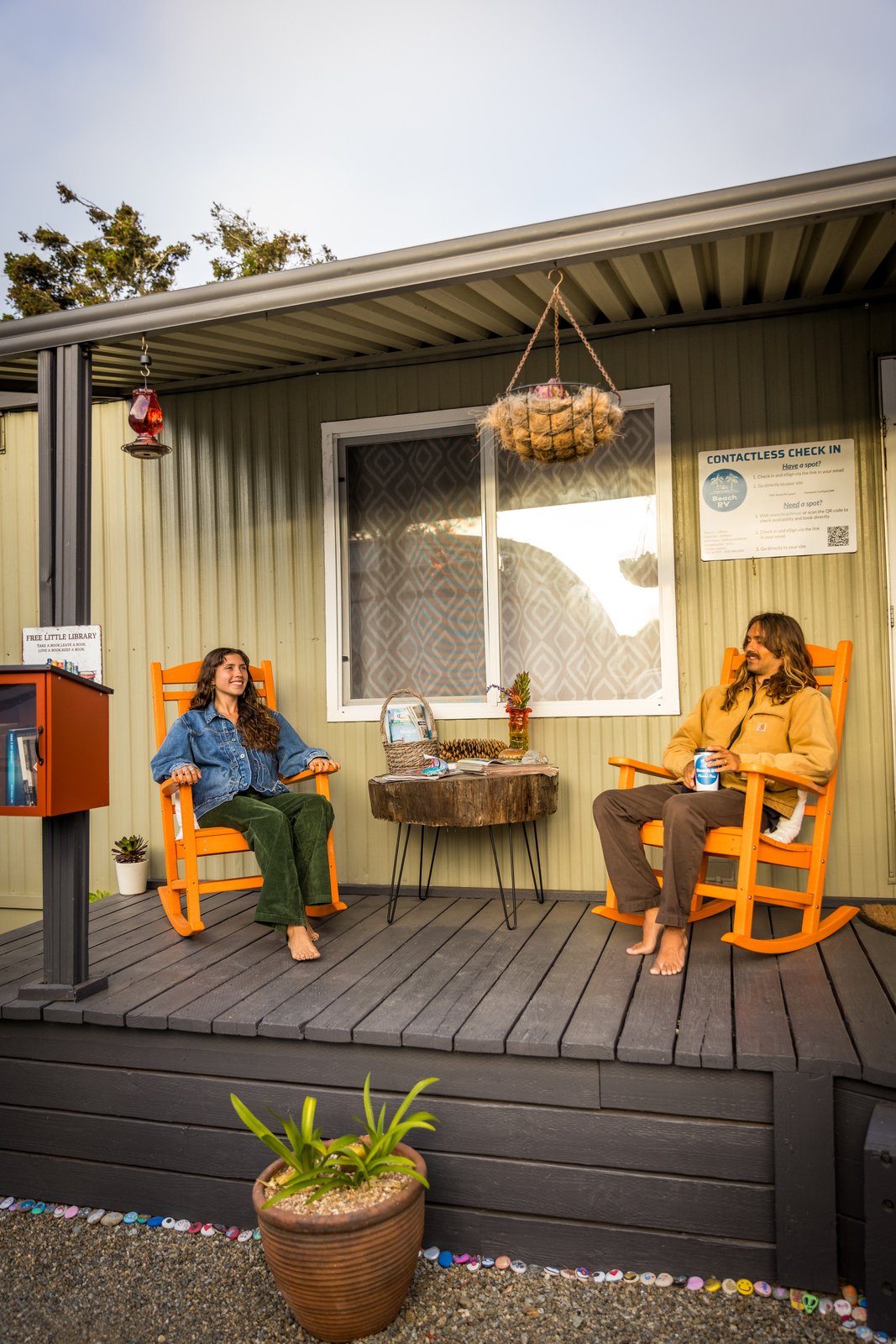 Two people seated in orange rocking chairs on the office porch at Beach RV Pleasure Point.