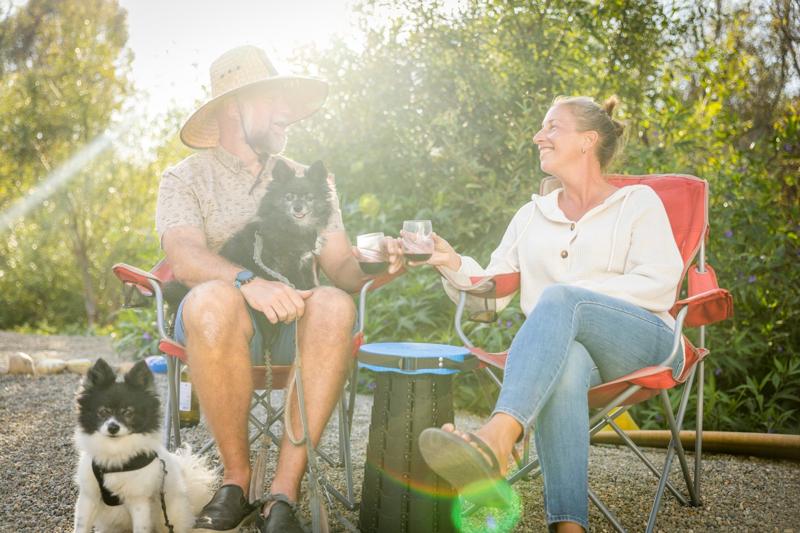 Two people toasting in camp chairs with two dogs at Beach RV Pleasure Point