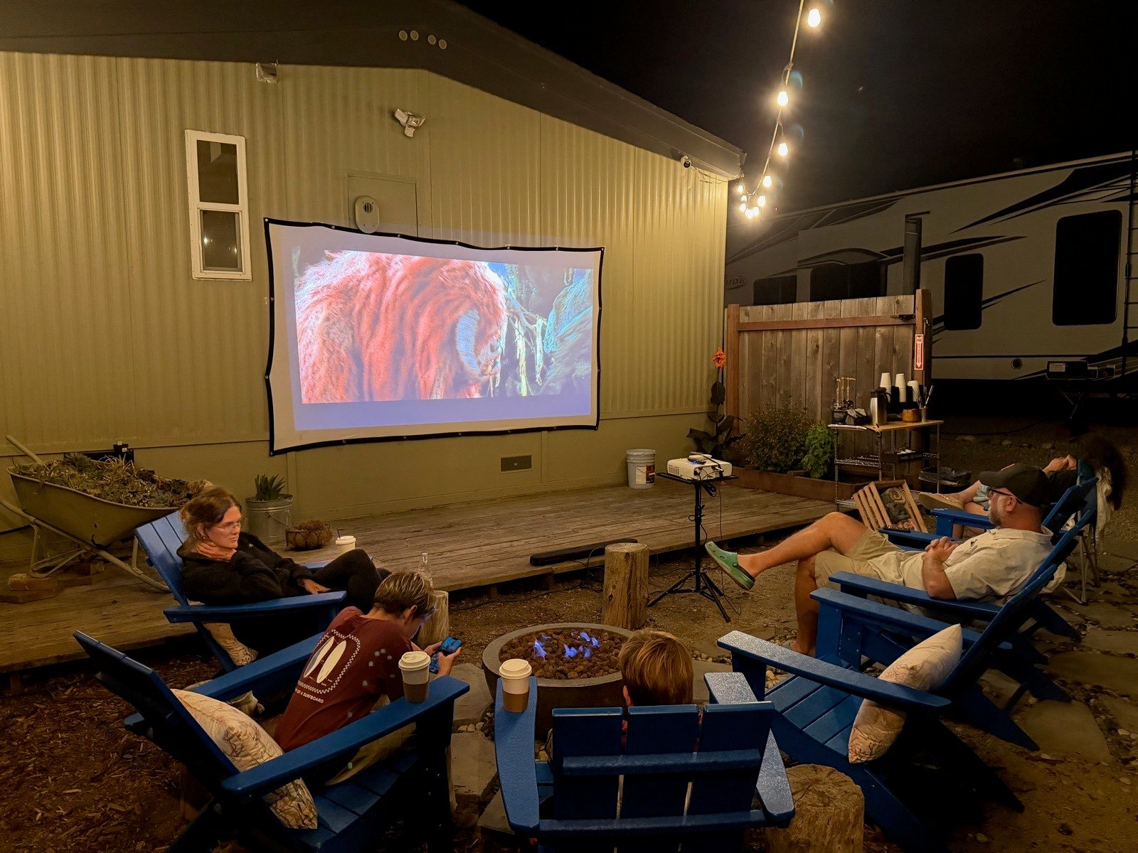 Families watching a movie outdoors on a screen at Beach RV Pleasure Point on a summer evening