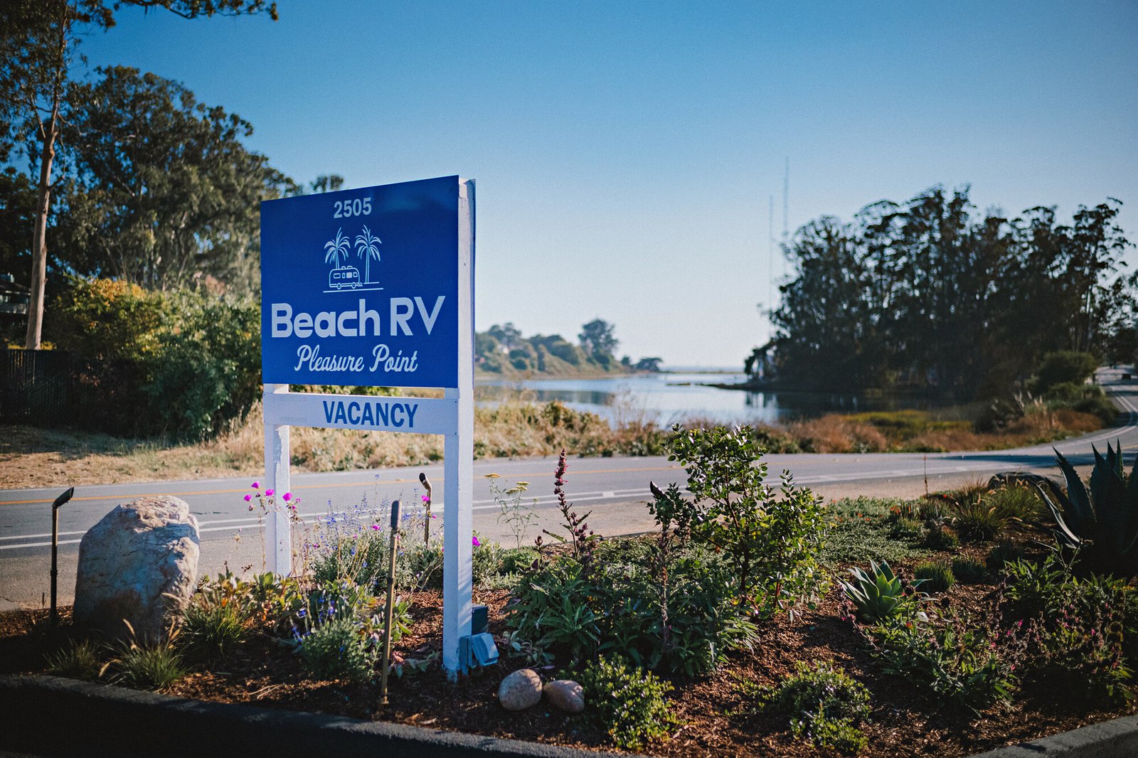 Beach RV Pleasure Point entrance sign and garden, with the lagoon across the road.