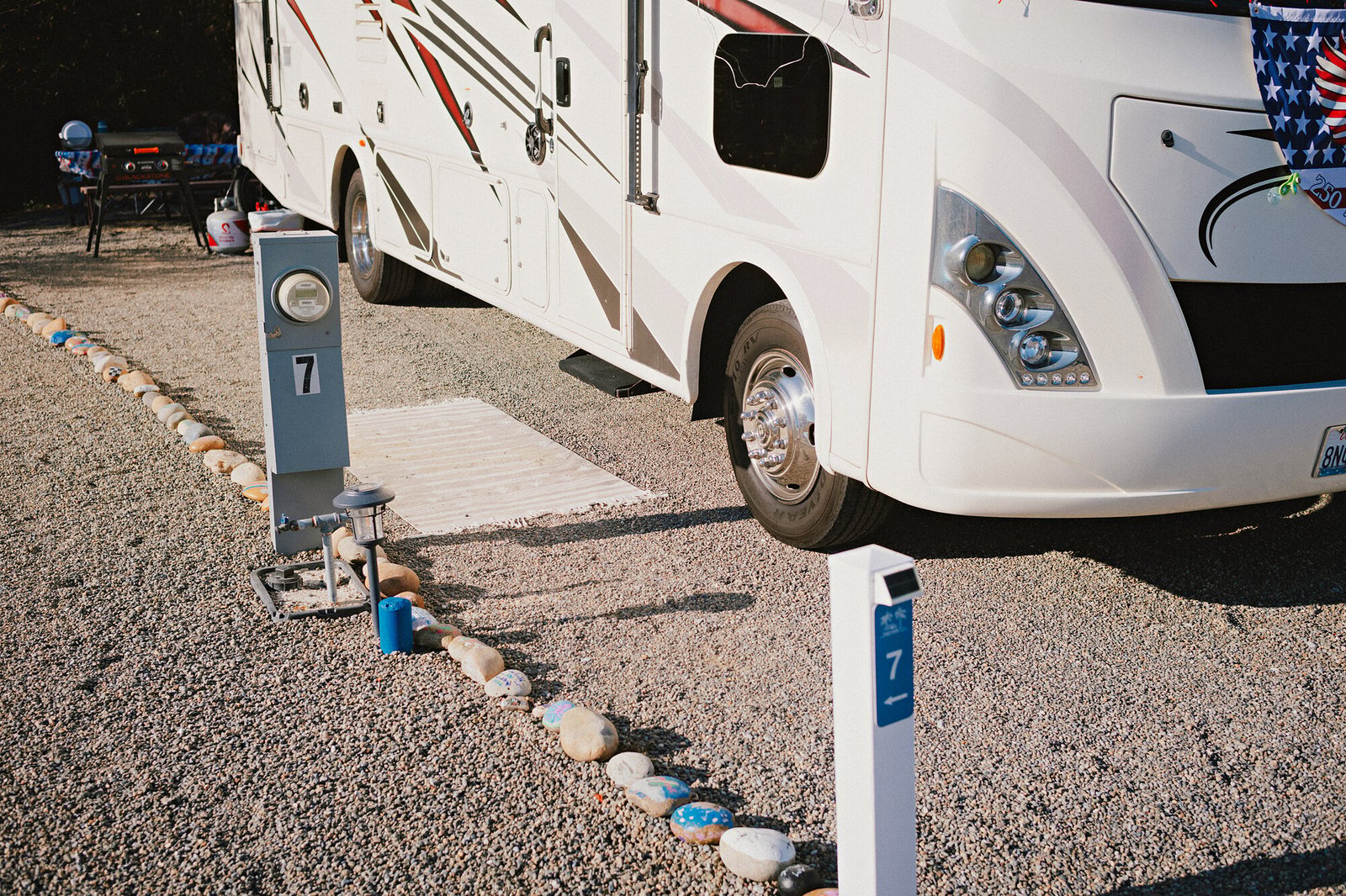 A motorhome beside the site 7 utility pedestal and painted-rock border at Beach RV Pleasure Point