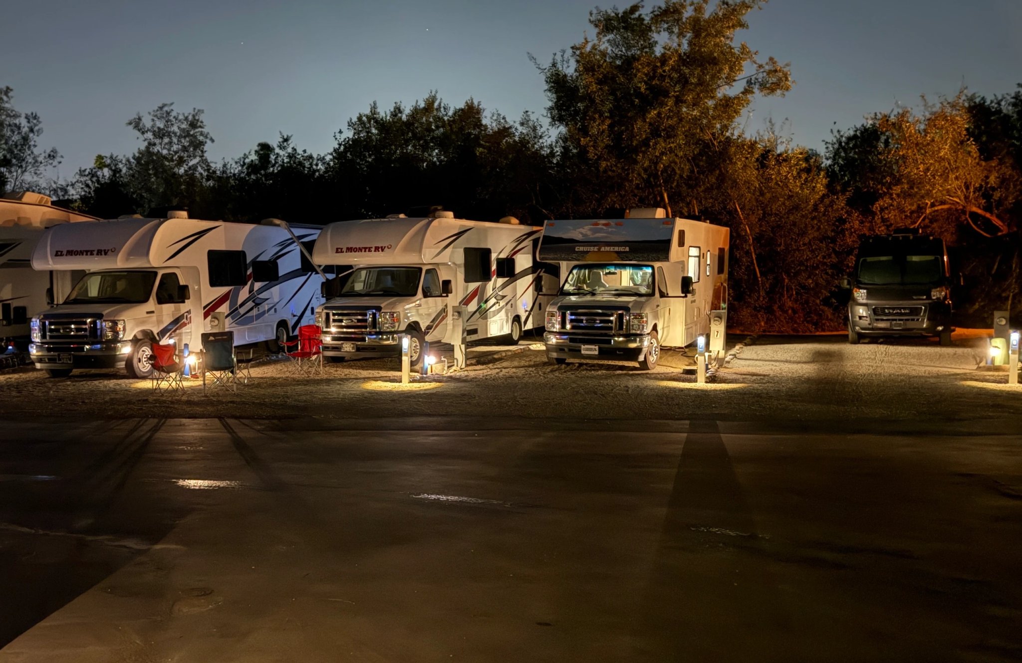 RVs settled in under warm site lights at dusk at Beach RV Pleasure Point
