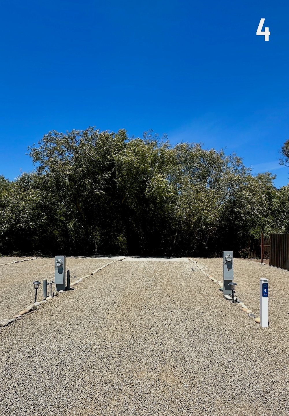 Empty Longboard site 4 showing the level gravel pad and full-hookup pedestals