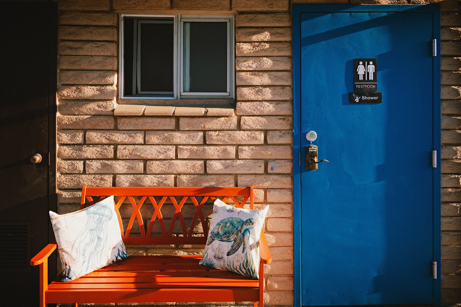 Orange bench beside the blue bathhouse door at Beach RV Pleasure Point