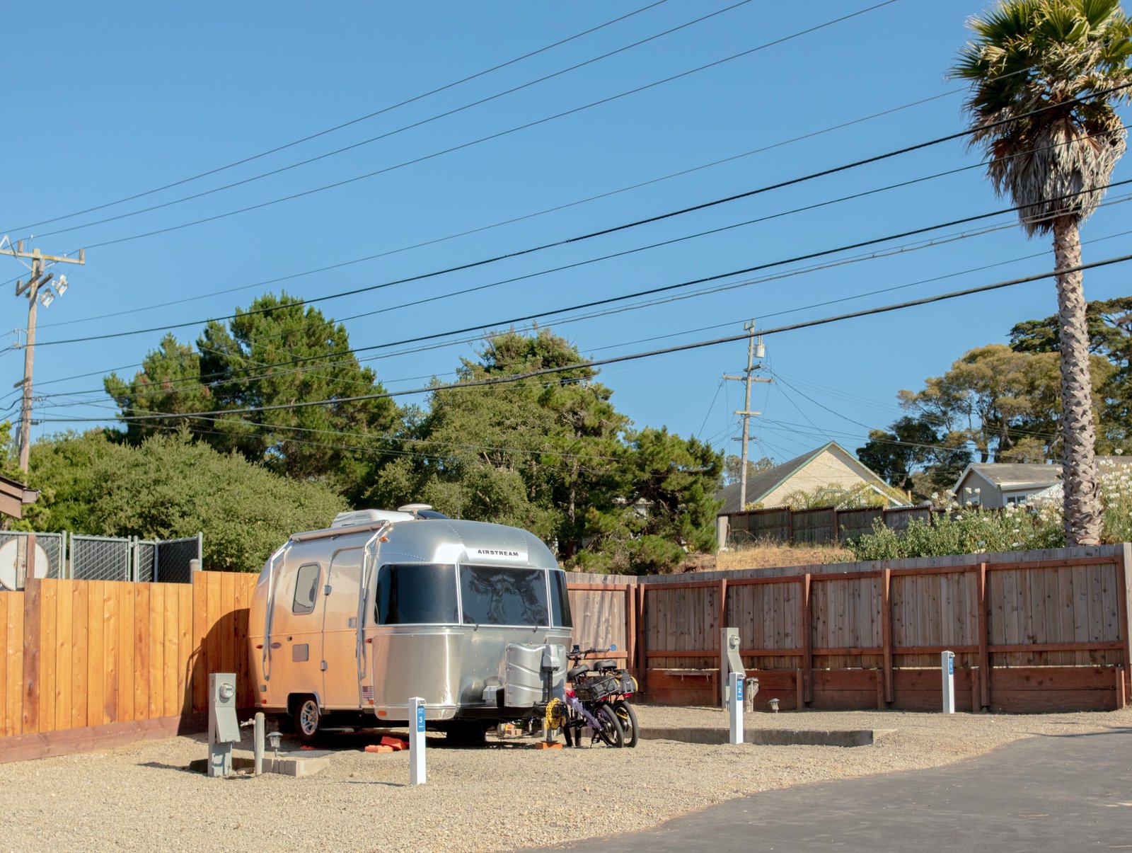 Airstream parked on a compact Snug site beside the red fence and palms