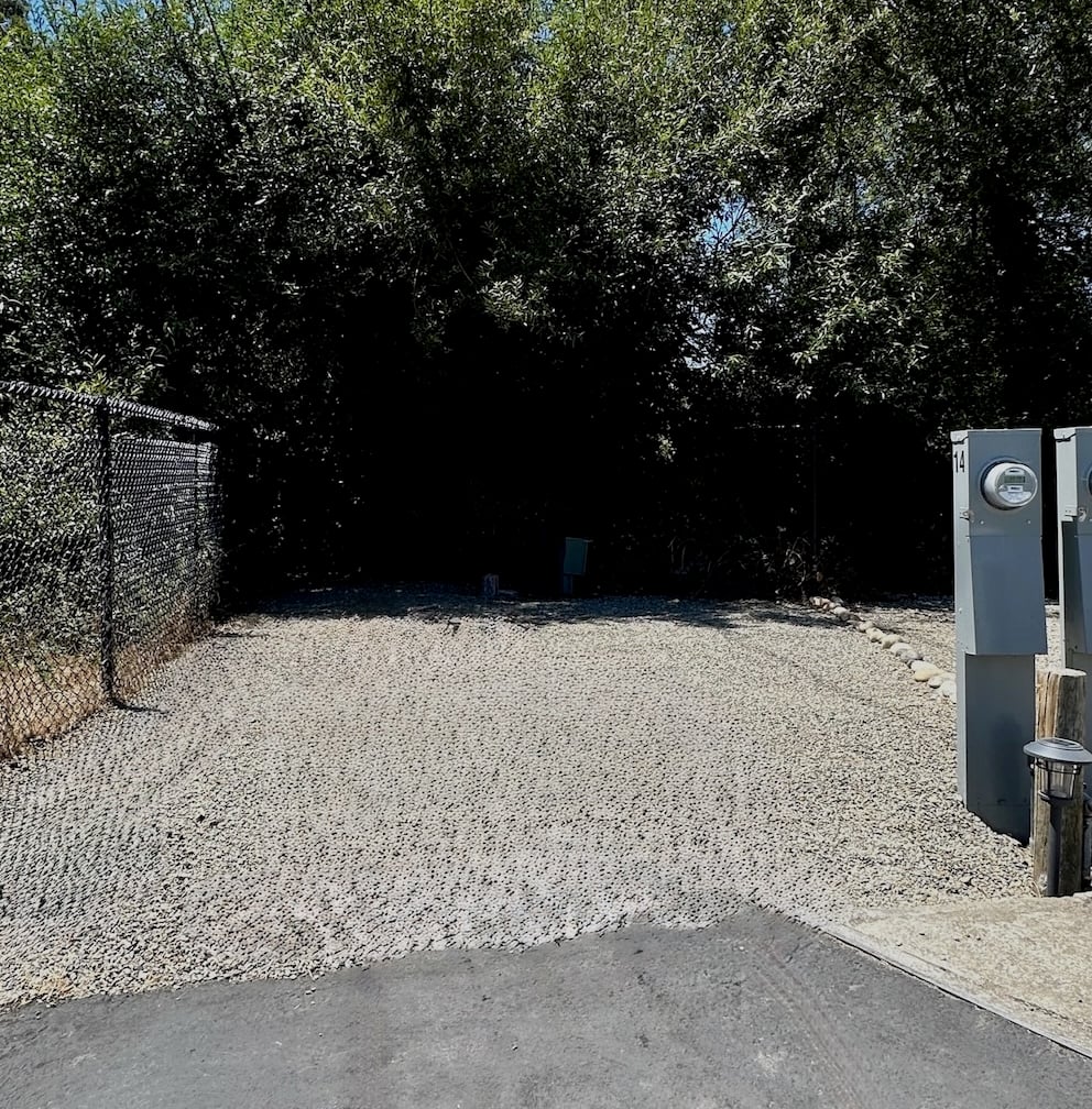 Empty Snug site with its full-hookup pedestal, shaded by the treeline