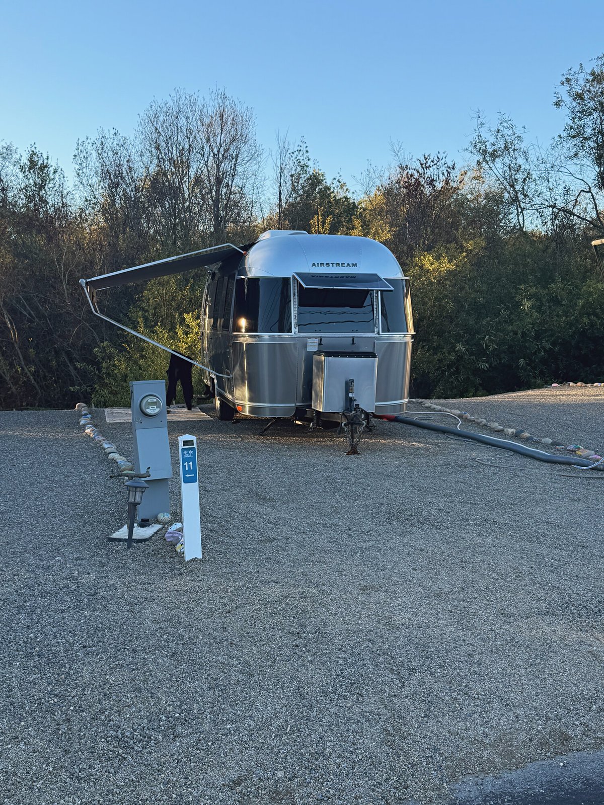 Airstream trailer with its awning out at dusk on Standard Plus site 11