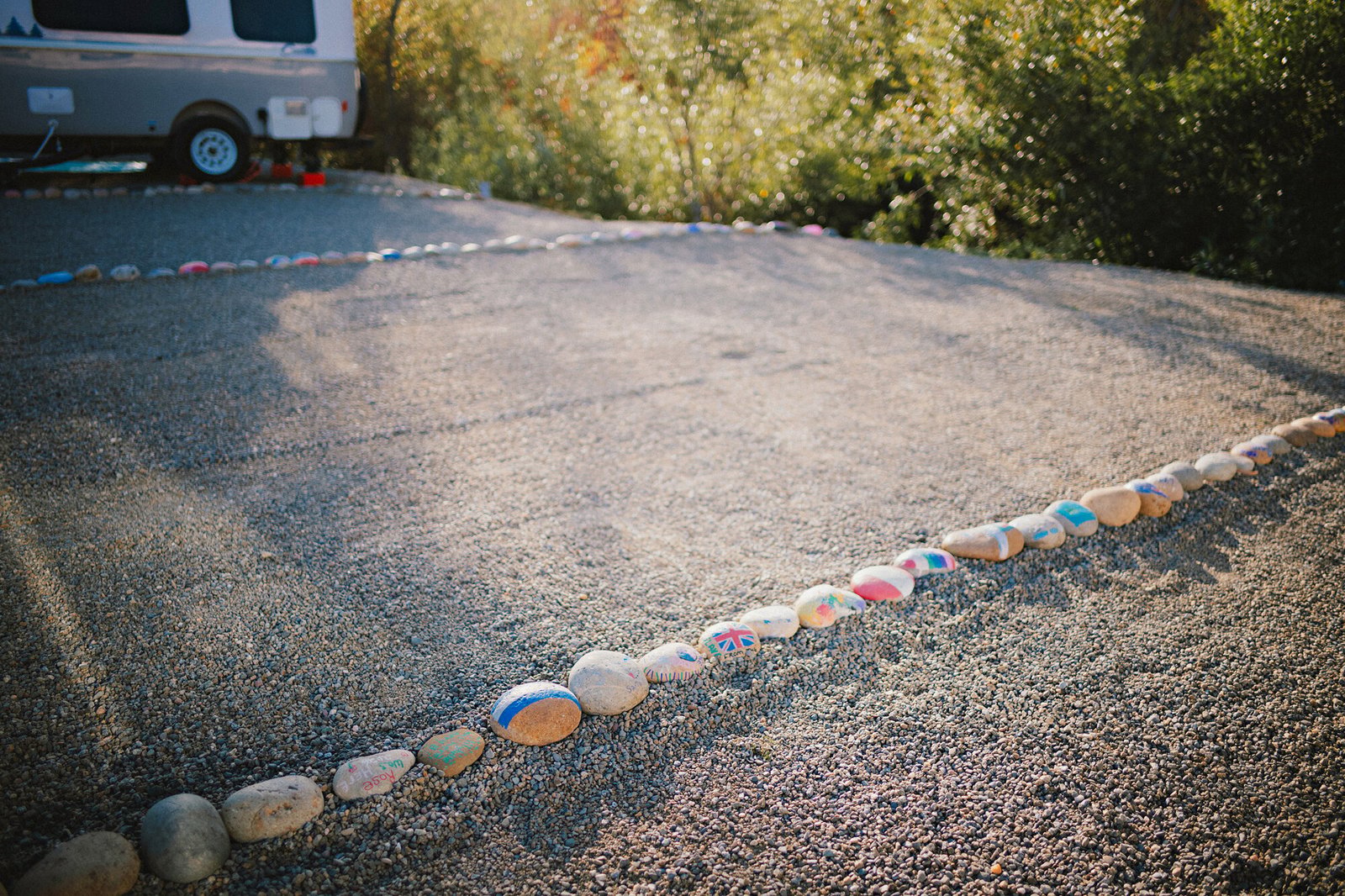Guest-painted rocks lining the edge of a creekside site