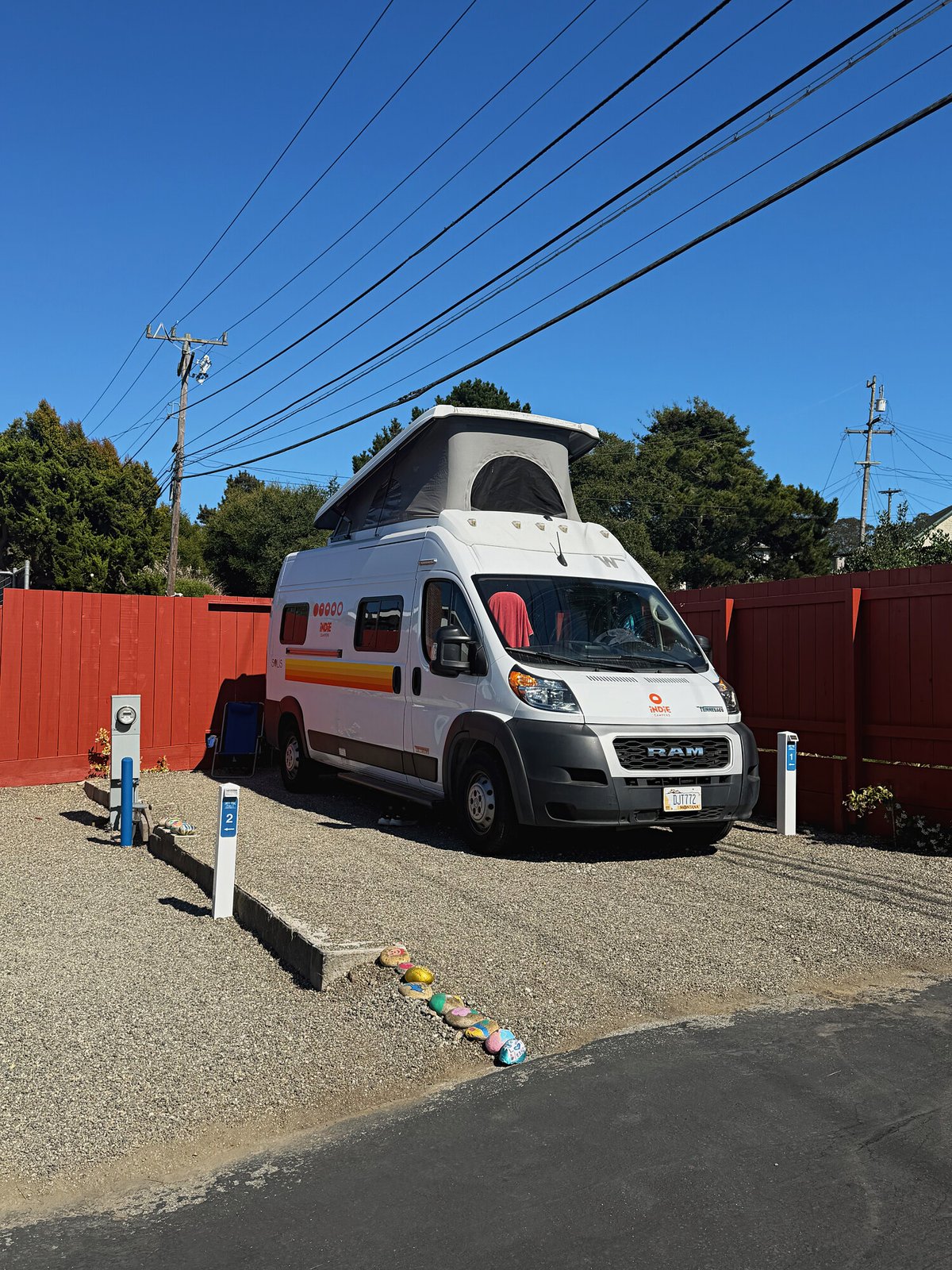 Pop-top campervan parked on Standard site 1 against the red fence