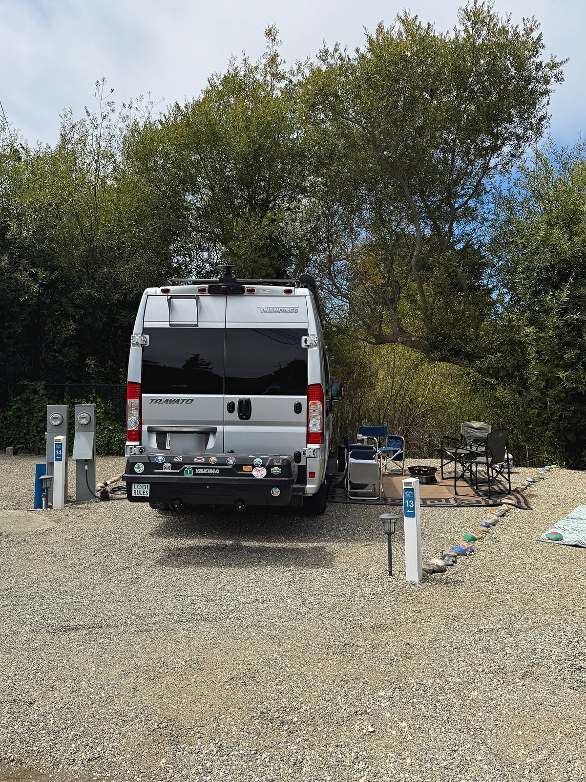 Travato camper van pulled in with patio chairs set up on Standard site 13