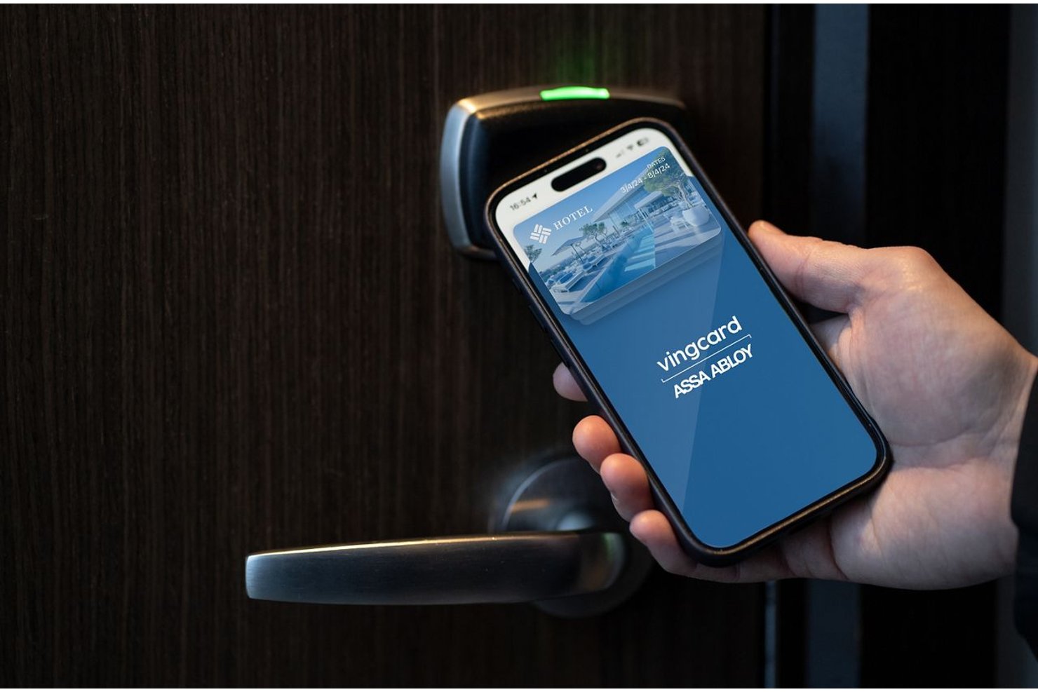 Hand som håller en smartphone med VingCard-appen nära ett elektroniskt hotelldörrlås.