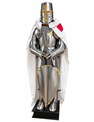 Armure templier en acier brillant sur socle noir, avec épée, bouclier et cape blanche à motif rouge.