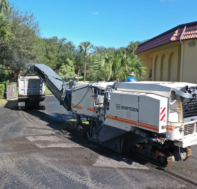 Asphalt milling machine preparing residential roadway for resurfacing