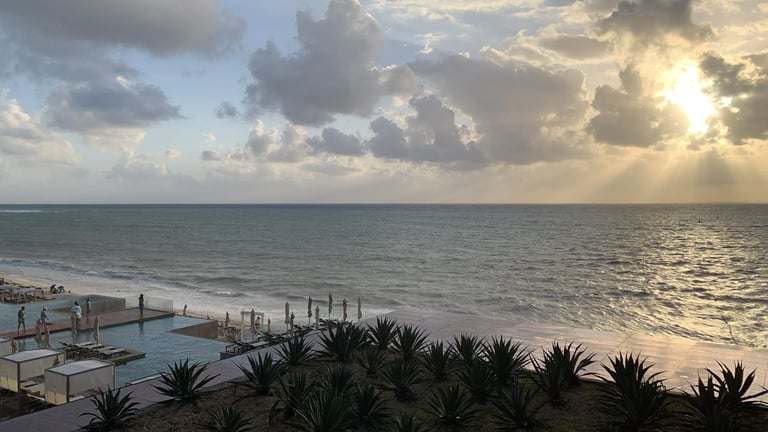 View of an ocean horizon with a cloudy sky and sun peaking through