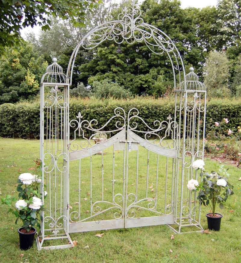 Ornamental metal gate arch in antiqued green finish with scrollwork detail