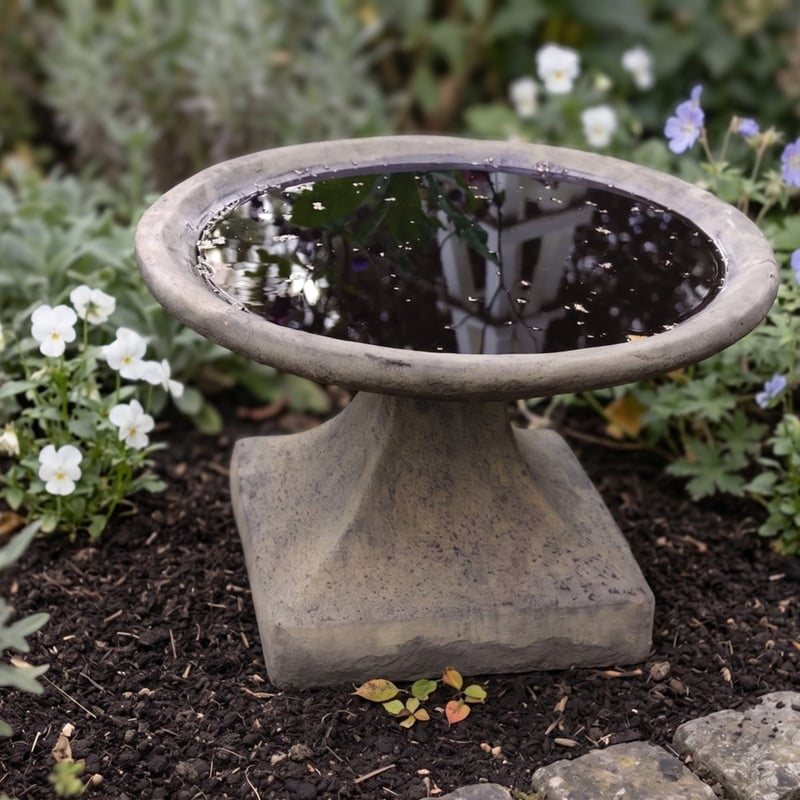 Low stone bird bath on a level garden base before winter