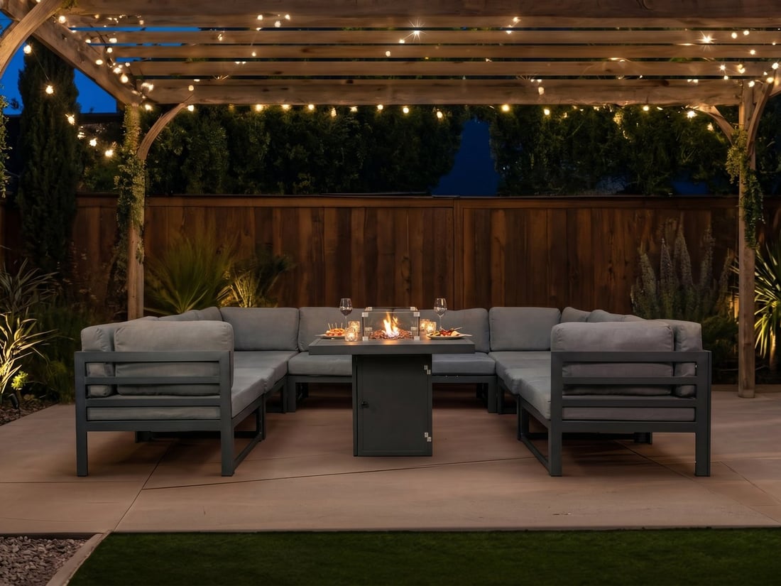 Anthracite modular 8-seater garden furniture set with lit fire pit table at dusk under festoon lights