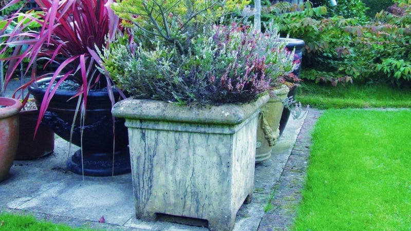 Garden pots and stone planters raised above a patio for winter drainage