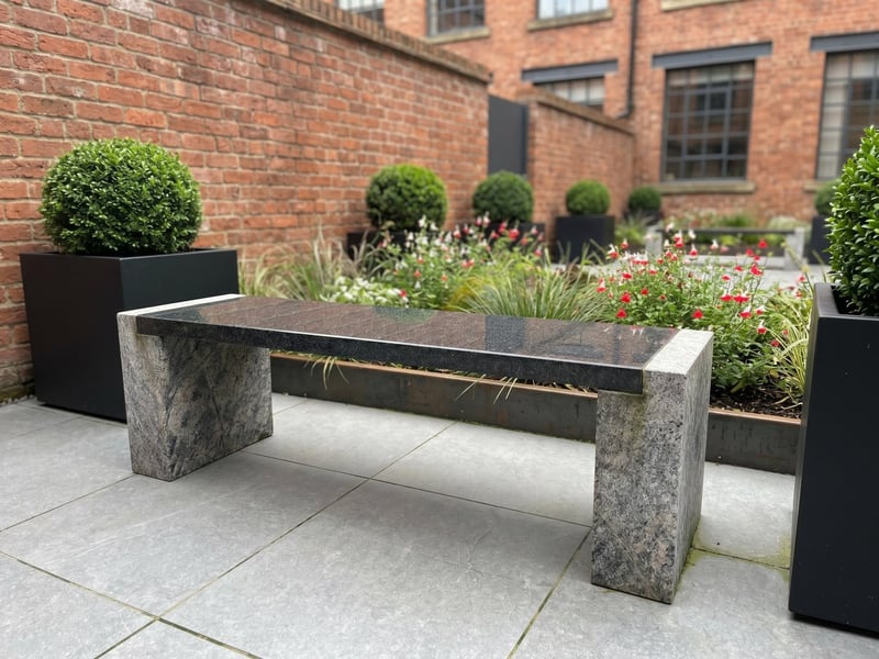 Epsom two-tone granite garden bench in a contemporary city courtyard with black planters and clipped box